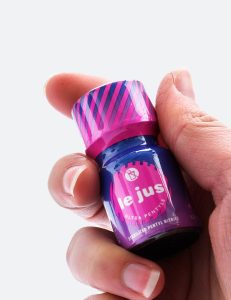 Poppers Le Jus dans la main avec flacon rose et bleu au pentyle